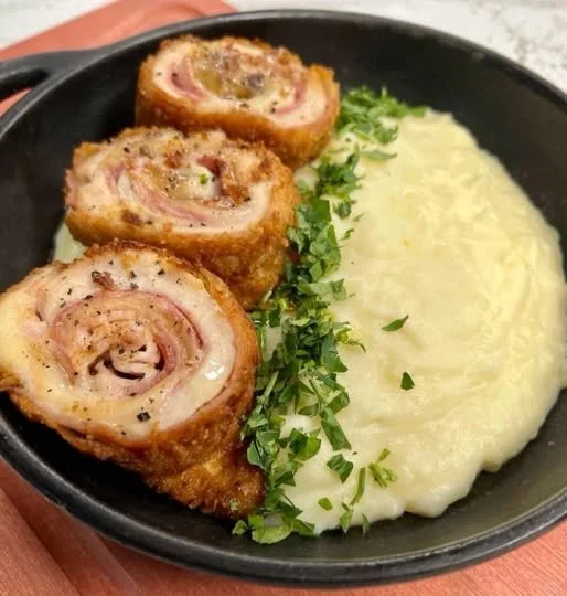 Plato de Cordon Bleu crujiente y dorado servido con guarnición.